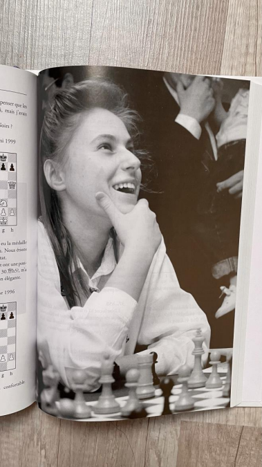 photo d'une page de livre avec une photo en noir et blanc d'une joueuse d'échecs souriante.